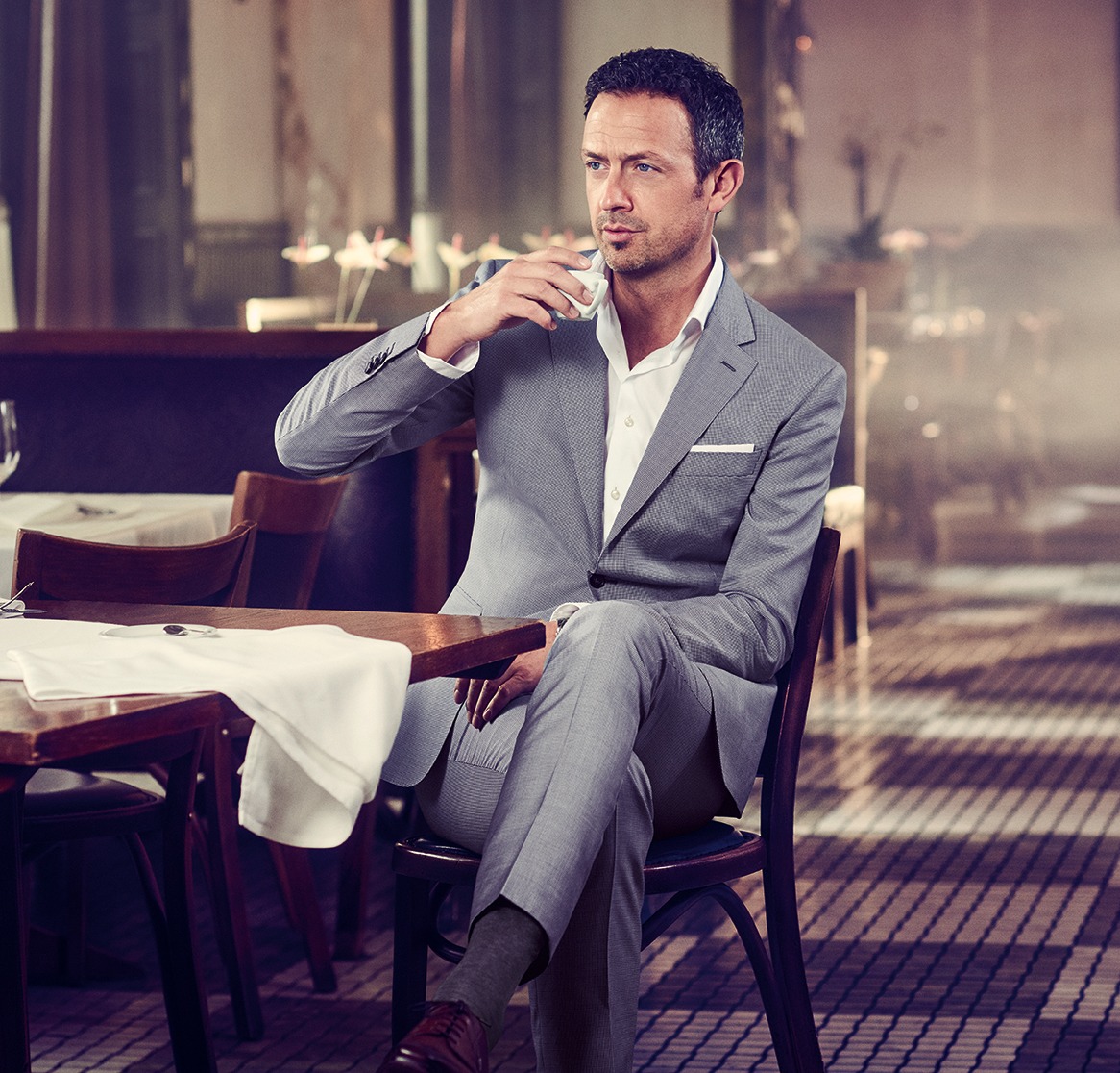 Till Brönner trägt einen hellgrauen Anzug, ein weißes Einstecktuch, ein weißes Hemd. Till Brönner trinkt Espresso im Café Callas
Till Brönner is wearing a light grey suit, a white pocket square and a white shirt. Till Brönner is drinking an espresso in the coffee callas